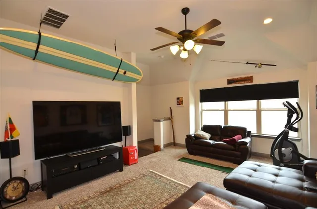 a living room with furniture a ceiling fan and a flat screen tv