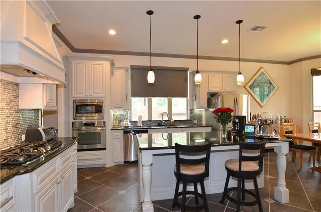 a kitchen with stainless steel appliances granite countertop table chairs stove and cabinets