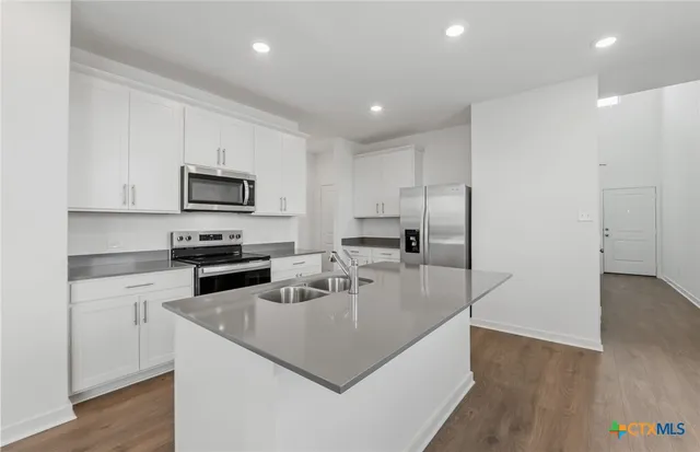 a kitchen with kitchen island a white counter top space a stove and cabinets