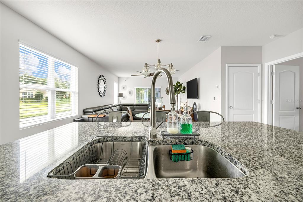 115 Duchess Road DeLand, FL 32724 - Photo 9 of 37 a kitchen with kitchen island granite countertop a sink stove and cabinets