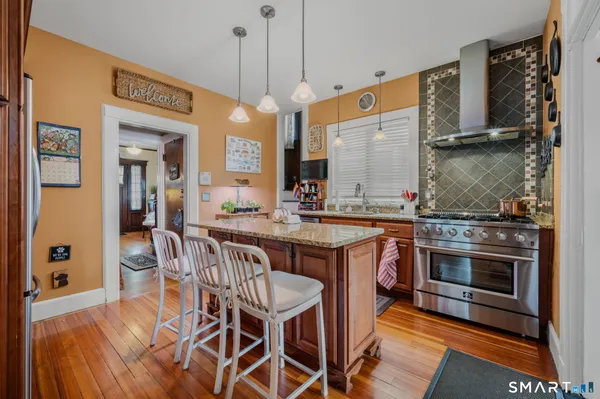 a kitchen with stainless steel appliances granite countertop a stove a sink dishwasher and a refrigerator with wooden floor