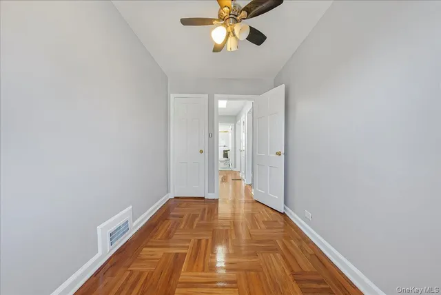 a view of a hallway with wooden floor and a bathroom