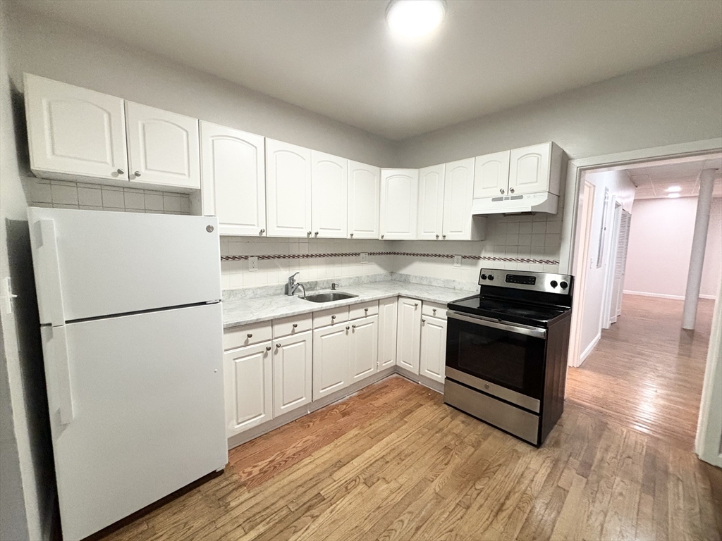 a kitchen with granite countertop a refrigerator stove top oven and sink
