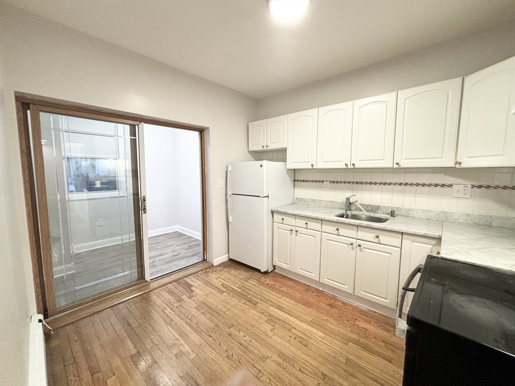 98 Main Street, Unit 1 Malden, MA 02148 - Photo 2 of 15 a kitchen with stainless steel appliances granite countertop a refrigerator and white cabinets