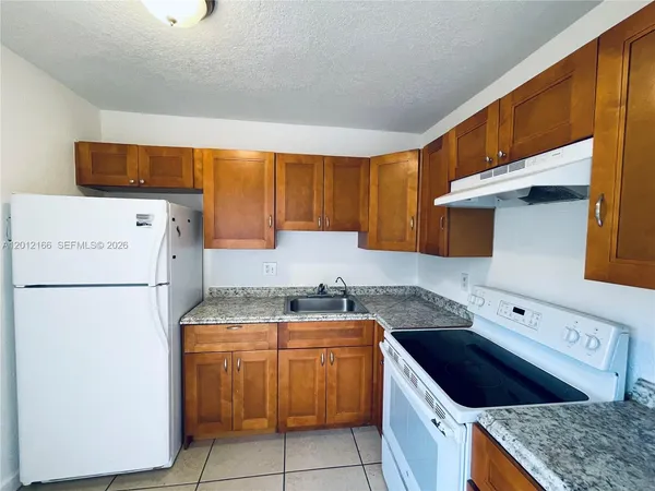a kitchen with a stove top oven a refrigerator a sink and white cabinets