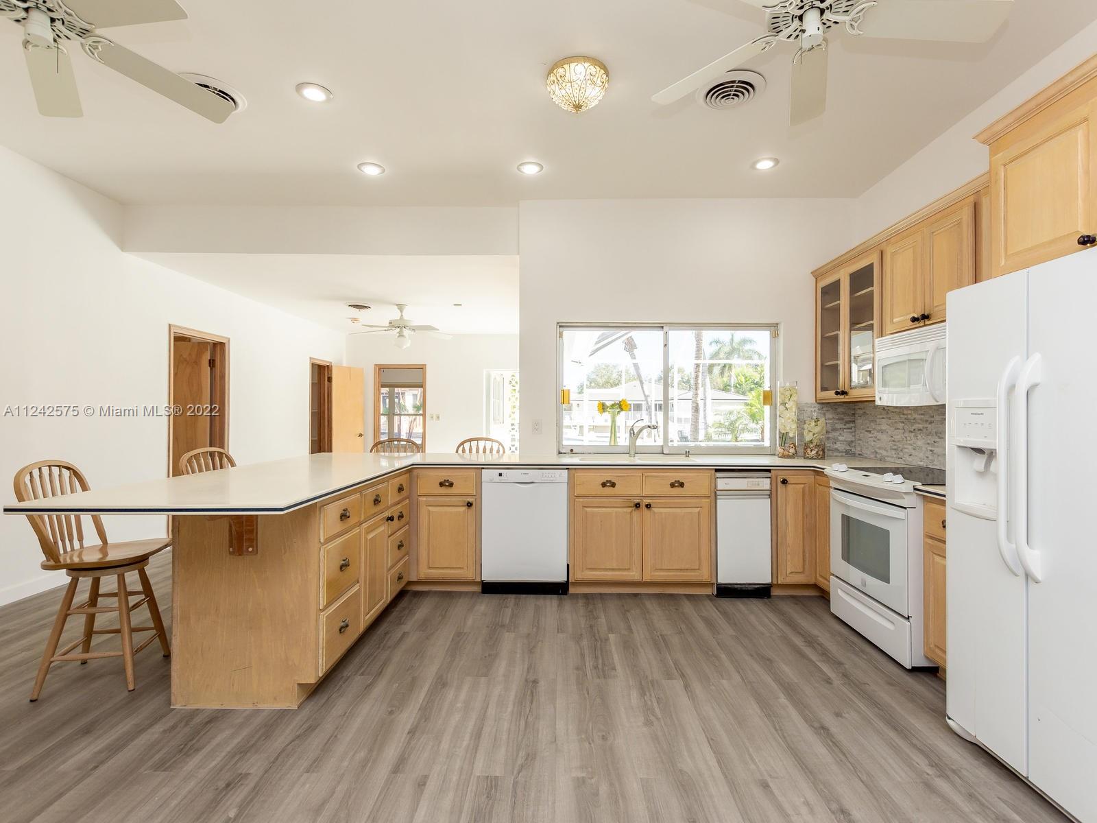 13001 Deva Street Coral Gables, FL 33156 - Photo 22 of 99 a kitchen with granite countertop white cabinets a sink a window and stainless steel appliances