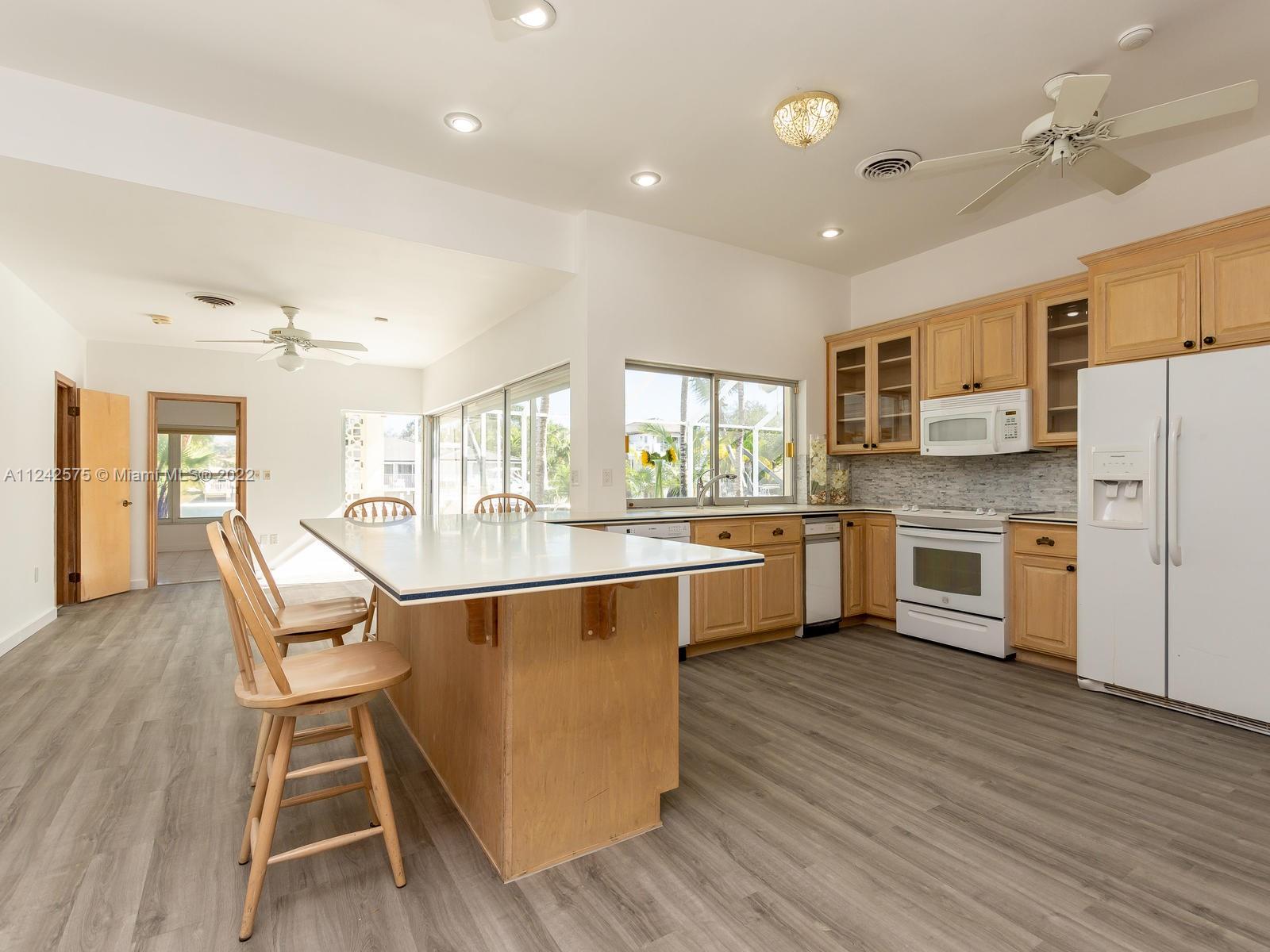 13001 Deva Street Coral Gables, FL 33156 - Photo 23 of 99 a large kitchen with stainless steel appliances granite countertop a stove a sink dishwasher a microwave oven and a dining table with wooden floor