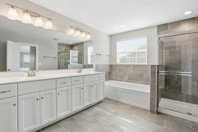a spacious bathroom with a double vanity sink a mirror and a bathtub