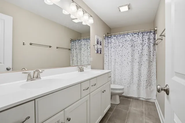 a bathroom with a double vanity sink toilet and shower