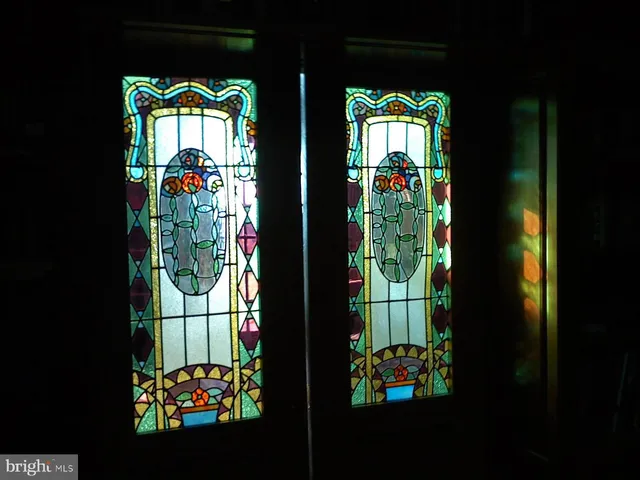 a living room with lots of books and a dining table with wooden floor