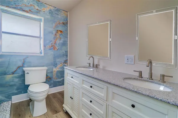 a bathroom with a granite countertop toilet sink and mirror