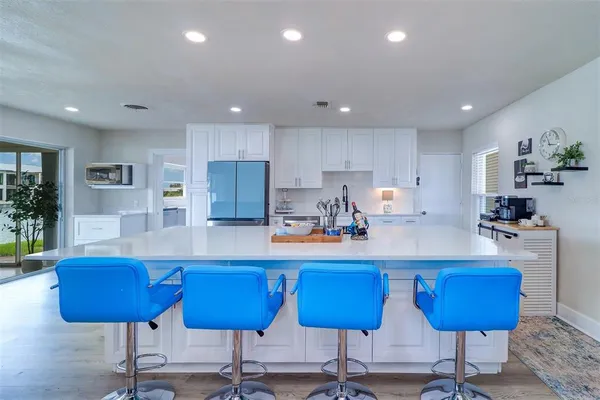 a kitchen with stainless steel appliances kitchen island granite countertop a table chairs sink and cabinets