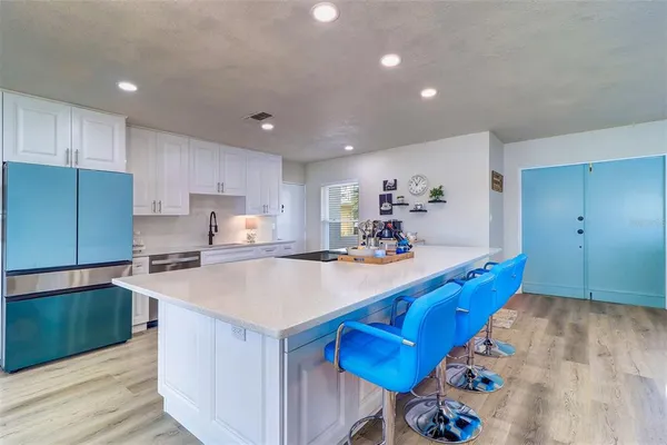 a kitchen with stainless steel appliances granite countertop a sink dishwasher and a refrigerator with wooden floor