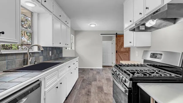 a kitchen with stainless steel appliances granite countertop a sink stove and cabinets