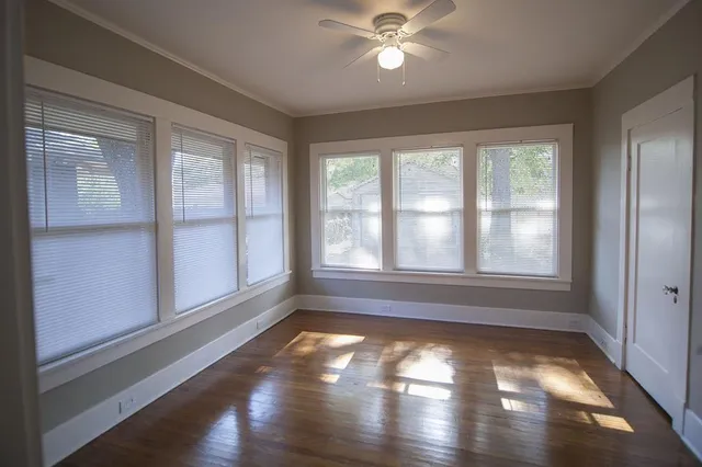 a view of empty room with wooden floor and fan