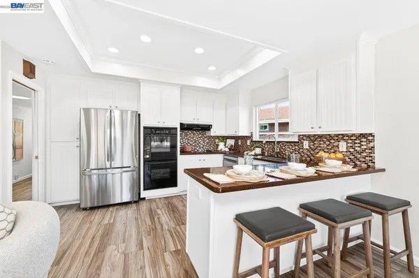 a kitchen with stainless steel appliances granite countertop a refrigerator a stove a sink and a microwave oven with wooden floor