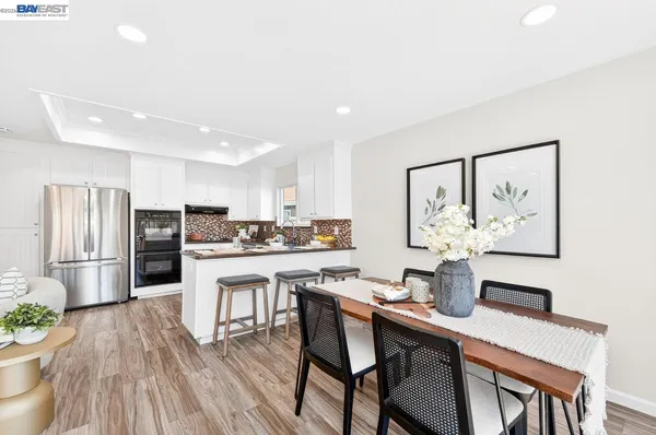 a kitchen with stainless steel appliances a dining table chairs and refrigerator