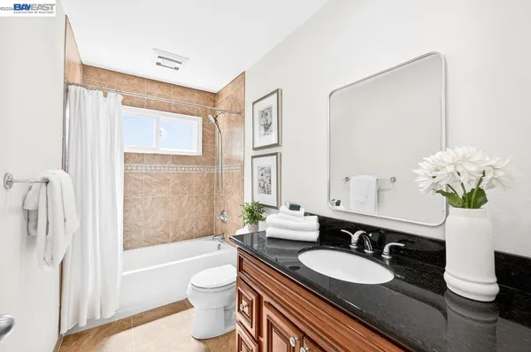 a bathroom with a granite countertop sink a toilet a mirror and bathtub
