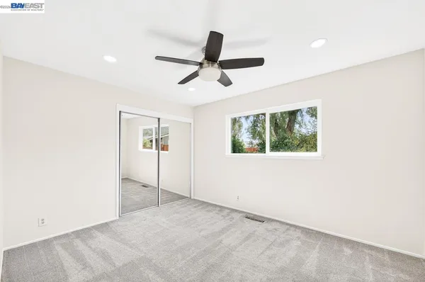 an empty room with windows and ceiling fan