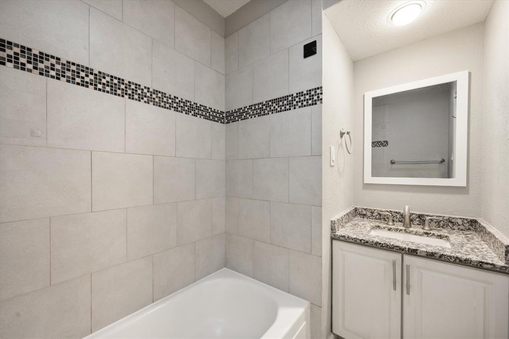 207 East Harwood Road, Unit 10 Euless, TX 76039 - Photo 28 of 34 a bathroom with a granite countertop sink a shower and a mirror