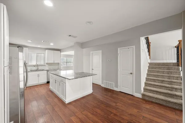 a hall with kitchen island granite countertop wooden floor and a granite counter top