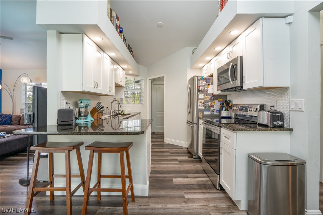 18367 Tulip Road Fort Myers, FL 33967 - Photo 7 of 13 a kitchen with stainless steel appliances granite countertop a stove top oven a refrigerator a sink and dishwasher with wooden floor