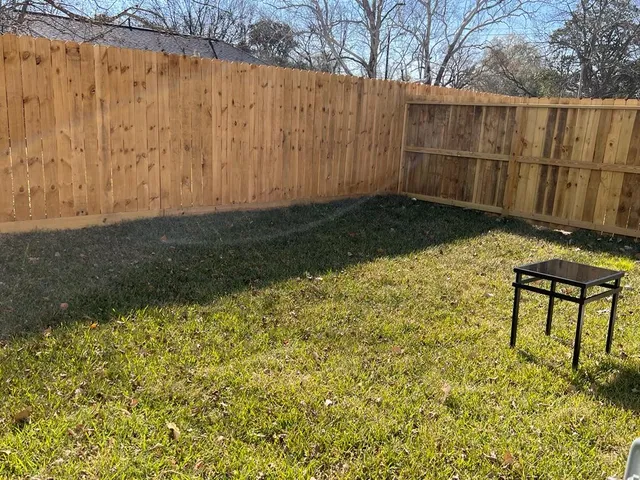 a view of a backyard with wooden fence