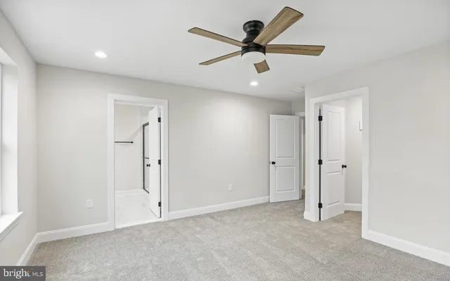 an empty room to hallway with a ceiling fan