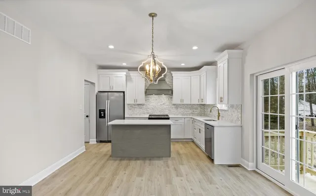 a kitchen with stainless steel appliances granite countertop a sink a stove a refrigerator and island with wooden floor