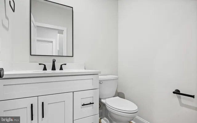 a bathroom with a toilet sink vanity and mirror