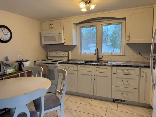 a kitchen with white cabinets and sink