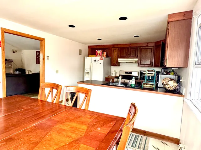 a kitchen with stainless steel appliances granite countertop a stove top oven a sink a dining table and chairs with wooden floor