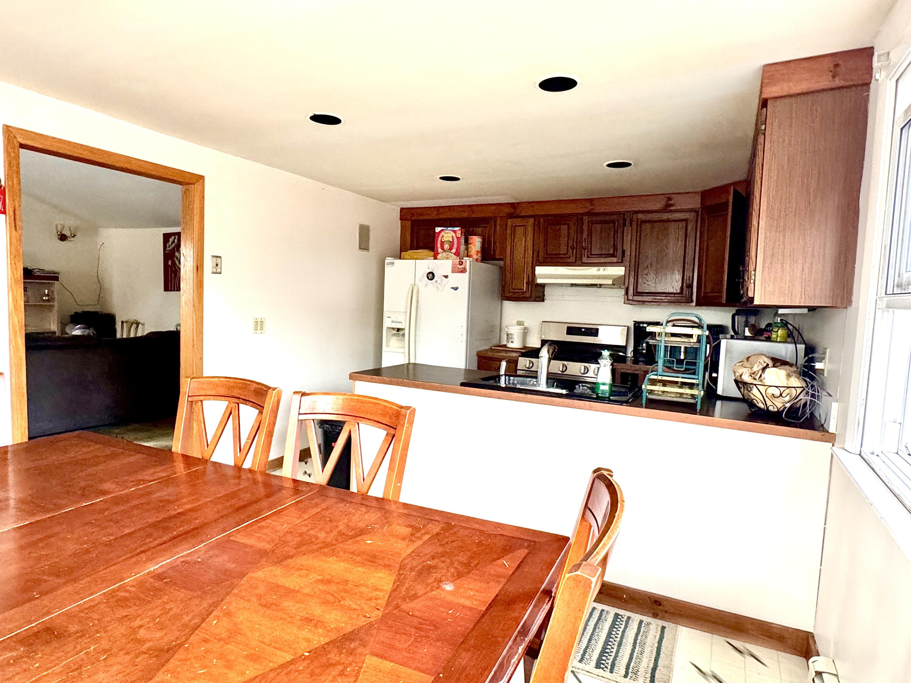 299 Winslow Gray Road West Yarmouth, MA 02673 - Photo 5 of 19 a kitchen with stainless steel appliances granite countertop a stove top oven a sink a dining table and chairs with wooden floor