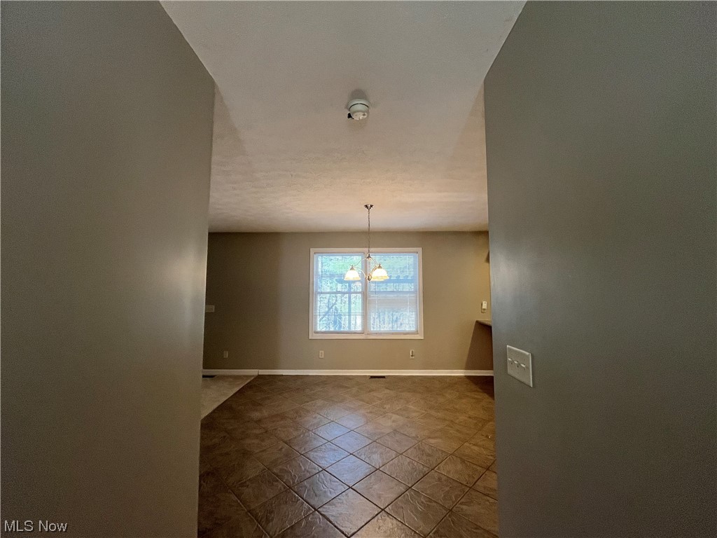 2819 Best Road Cambridge, OH 43725 - Photo 26 of 33 Tiled empty room featuring an inviting chandelier