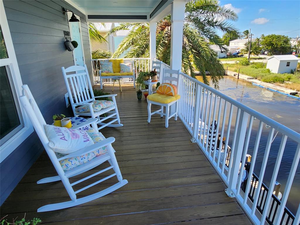 31547 Ave D Big Pine Key, FL 33043 - Photo 3 of 42 a balcony with wooden floor table and chairs