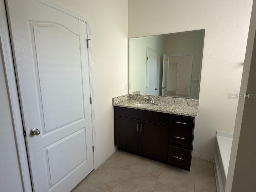 7604 Oakmoss Loop Davenport, FL 33837 - Photo 12 of 16 a bathroom with a granite countertop sink and a mirror
