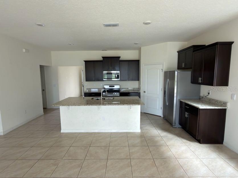 7604 Oakmoss Loop Davenport, FL 33837 - Photo 4 of 16 a large kitchen with cabinets and stainless steel appliances