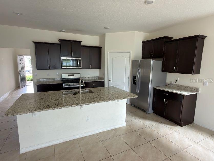 7604 Oakmoss Loop Davenport, FL 33837 - Photo 5 of 16 a kitchen with stainless steel appliances granite countertop a refrigerator a stove and a sink with granite countertops