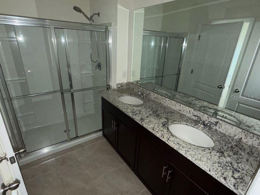 7604 Oakmoss Loop Davenport, FL 33837 - Photo 9 of 16 a bathroom with a granite countertop shower sink vanity and mirror