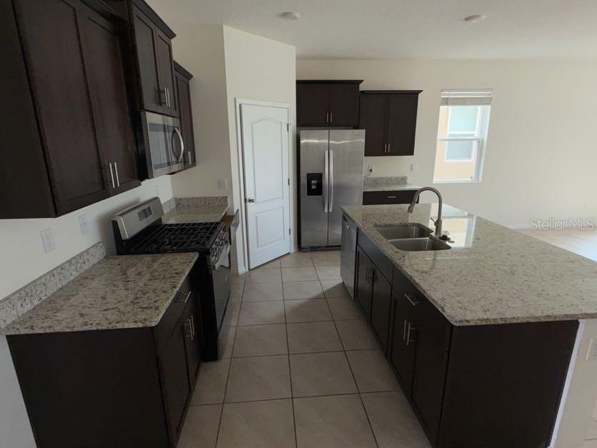 7604 Oakmoss Loop Davenport, FL 33837 - Photo 10 of 16 a kitchen with stainless steel appliances granite countertop a sink stove and refrigerator