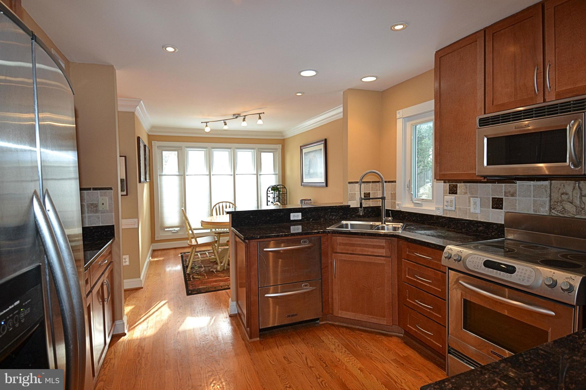 11634 Chapel Cross Way Reston, VA 20194 - Photo 4 of 30 a kitchen with stainless steel appliances granite countertop a stove a sink dishwasher a refrigerator and a microwave oven with wooden floor