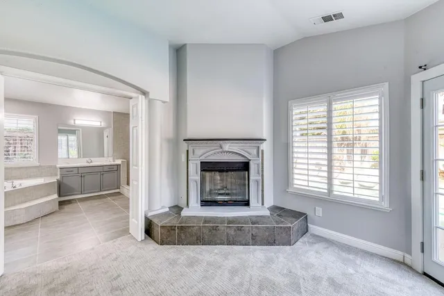 an empty room with windows and fireplace