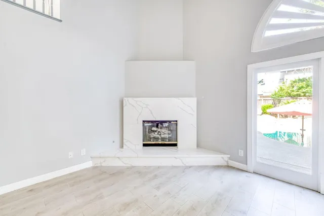 an empty room with wooden floor mirror and windows