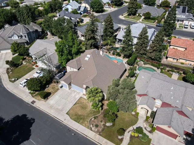 an aerial view of a house with yard and swimming pool