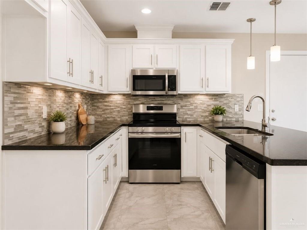 707 Palmer Road, Unit 3 Mission, TX 78573 - Photo 3 of 8 U-shaped kitchen featuring white cabinetry with brushed nickel hardware, dark countertops, a mosaic tile backsplash, and stainless steel appliances