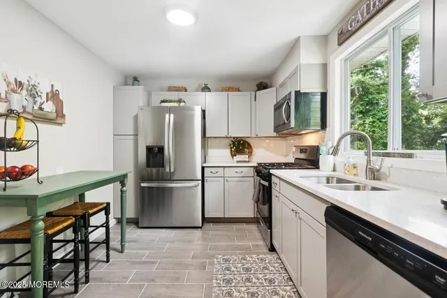 a kitchen with a sink cabinets stainless steel appliances and a window