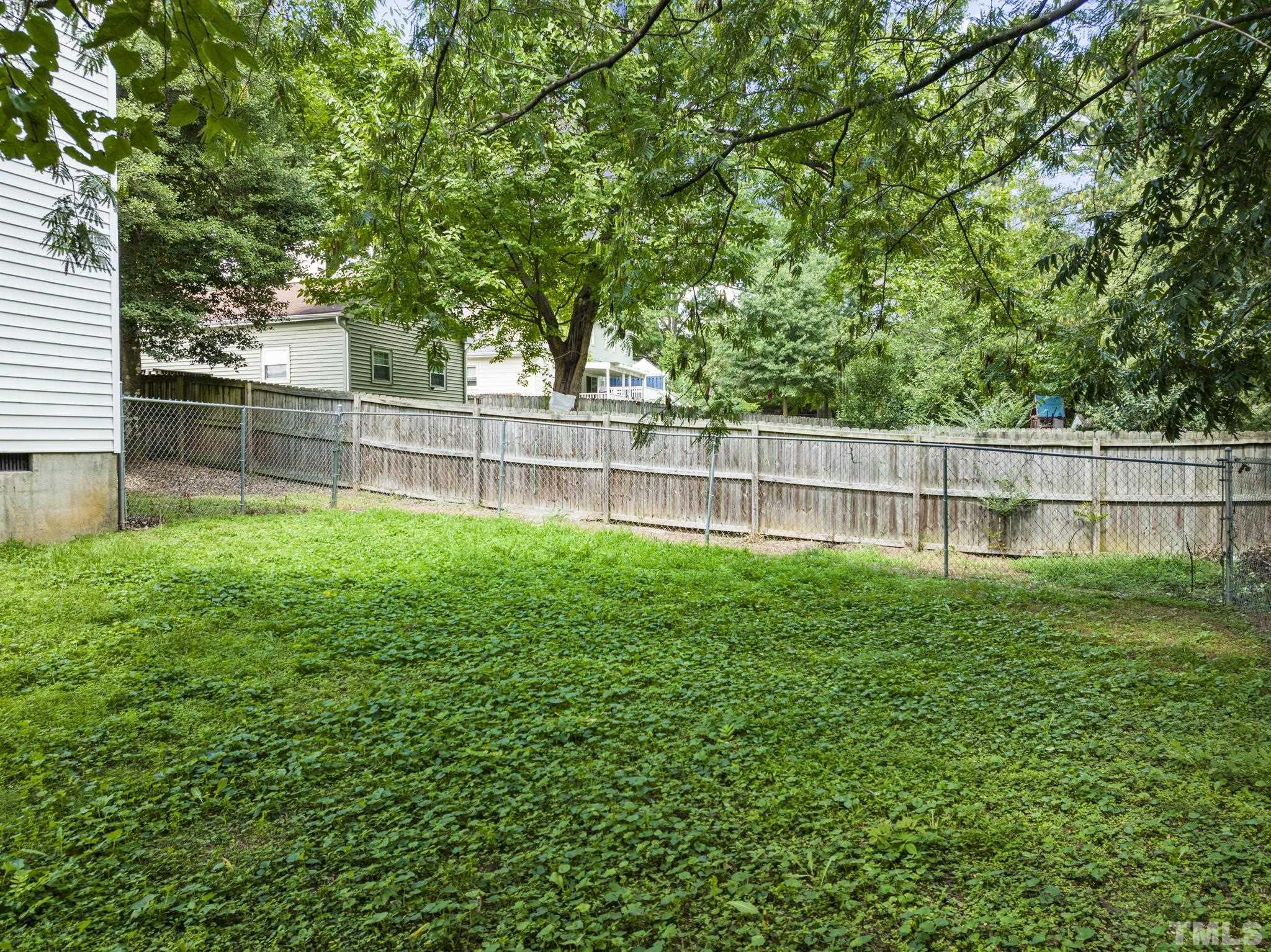 405 Jones Franklin Road Raleigh, NC 27606 - Photo 20 of 41 a view of a yard with a large tree and wooden fence