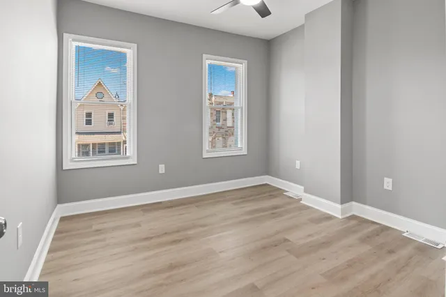 a view of an empty room with window and wooden floor
