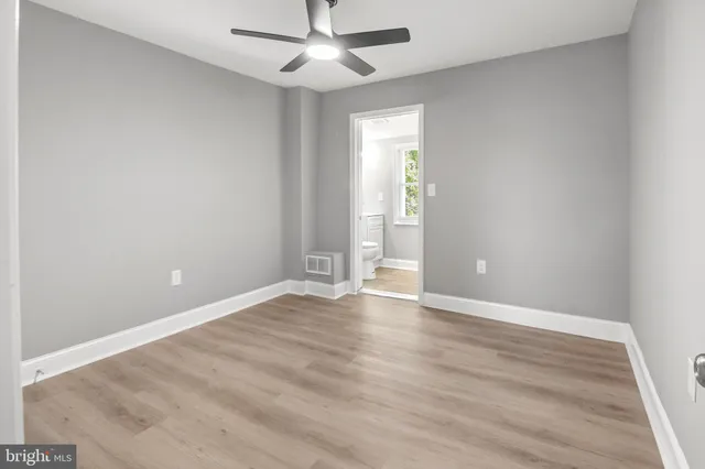an empty room with wooden floor ceiling fan and windows