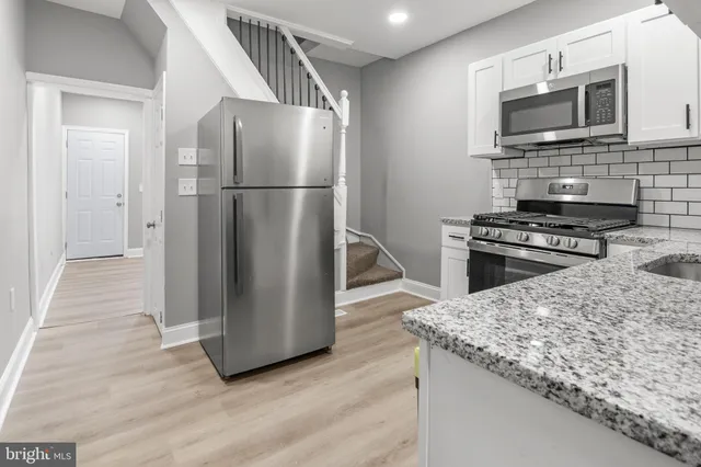 a kitchen with granite countertop a refrigerator and a stove top oven